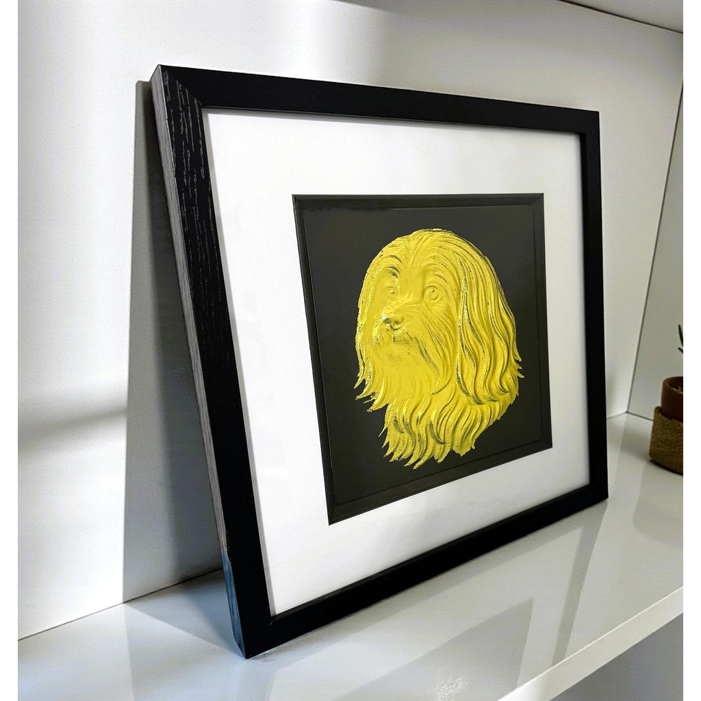 Maltese gold leaf wall art photographed at an angle on a shelf with black frame and white mount