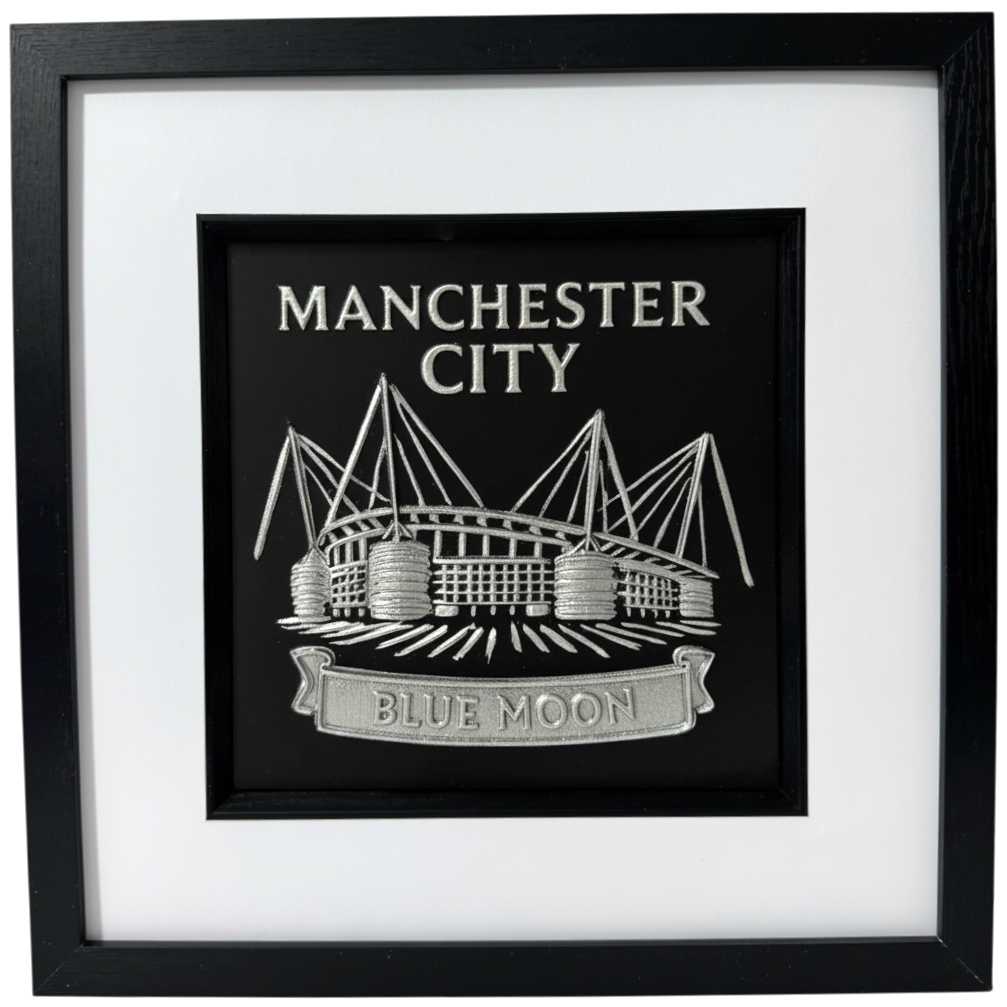 Silver 3D relief wall art of Manchester City Etihad Stadium on black background.