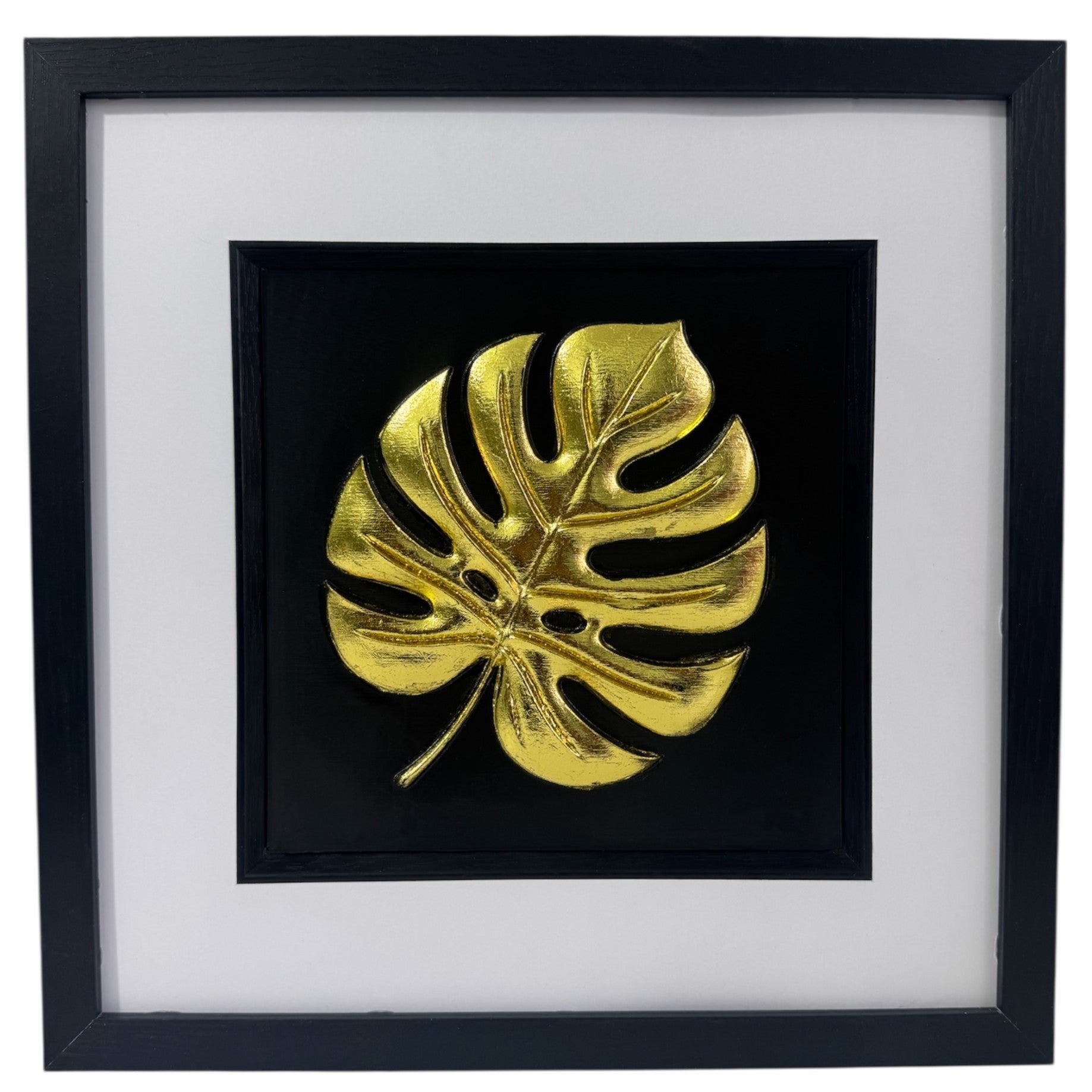 Gold monstera leaf 3D relief in black box frame with white mount and glass front, product photo