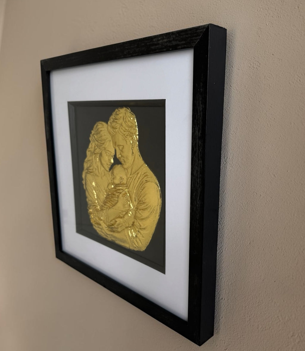 Angled close view of Gold family artwork showing raised relief detail inside a black framed display.