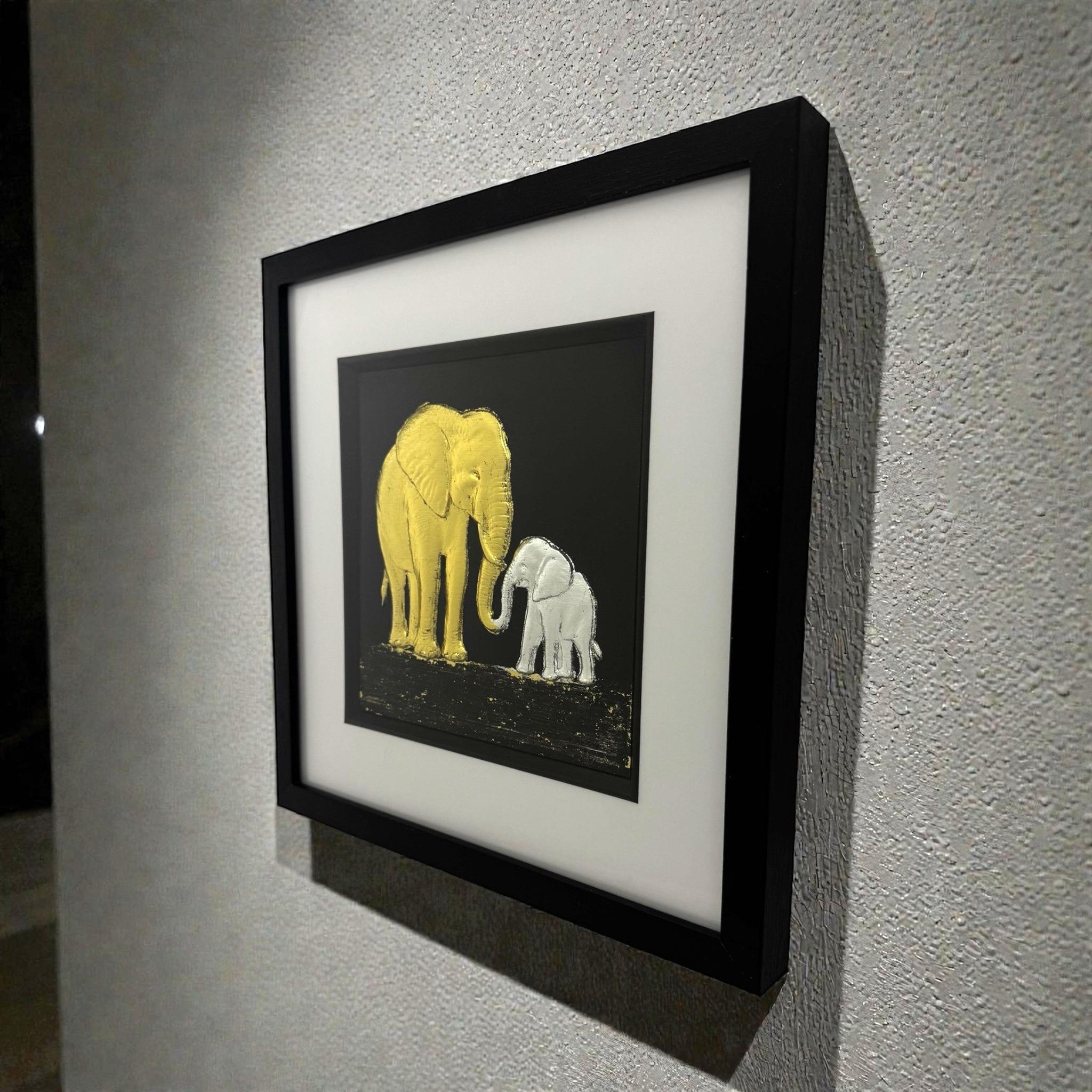 Framed elephant mother and baby wall art mounted on a wall, shown at an angle highlighting depth and texture