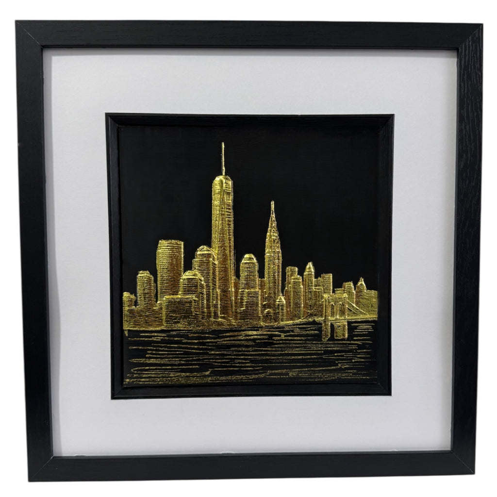 Framed New York skyline wall art in gold leaf, front view showing city silhouette above water on black background