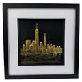 Framed New York skyline wall art in gold leaf, front view showing city silhouette above water on black background