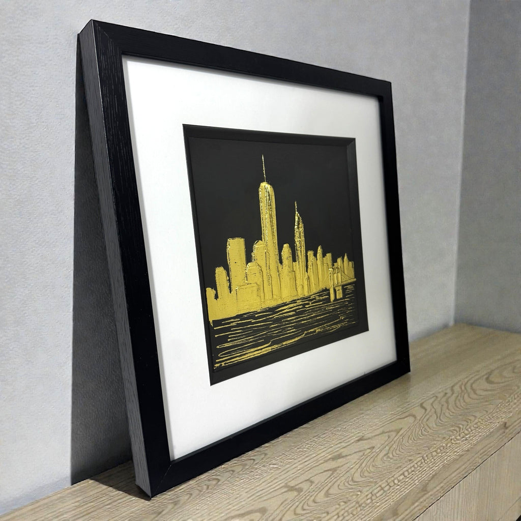 Angled view of gold leaf New York skyline wall art showing frame depth, raised relief texture, and metallic highlights