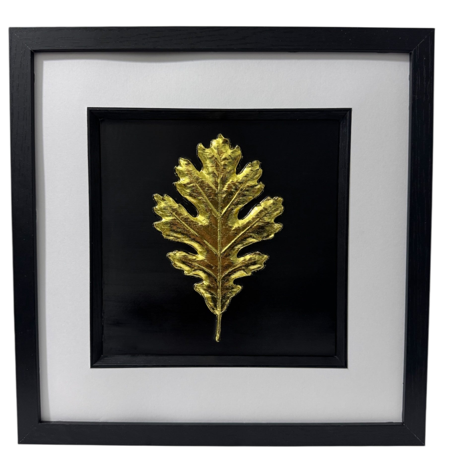Oak leaf relief artwork finished in Gold Leaf on a black background in a black box frame with crisp white mount, front view