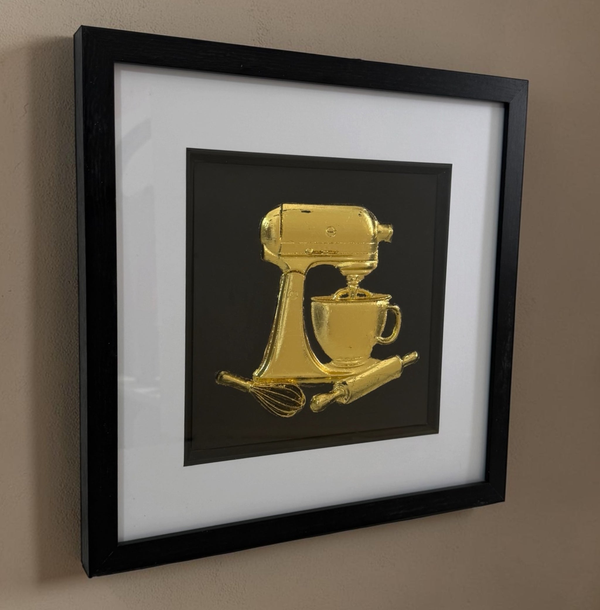Angled gold stand mixer framed artwork showing raised relief detail through the glass front.