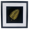Gold palm leaf wall art framed in black with white mount, raised relief palm leaf on a deep black background