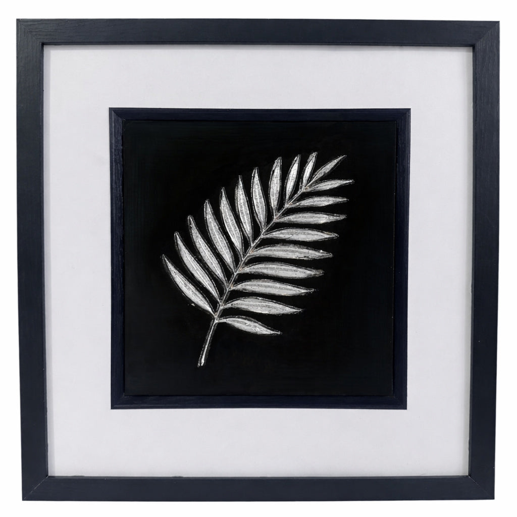 Silver palm leaf wall art framed in black with white mount, raised relief palm frond on a black background