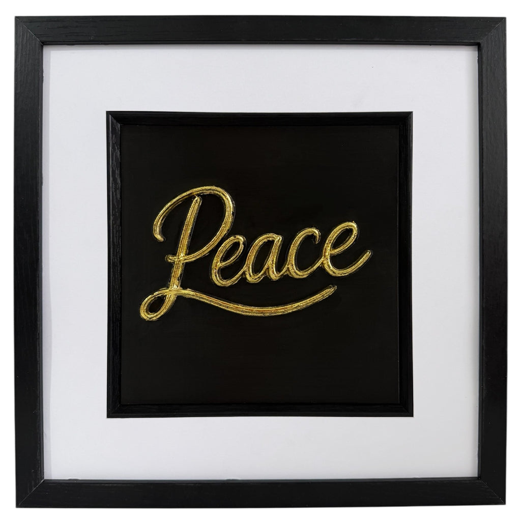 Gold framed Peace word artwork with raised script lettering, black centre, white mount and black square frame.