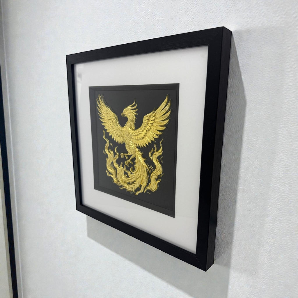 Framed gold phoenix rising wall art displayed on a wall, black frame with white mount and sculpted phoenix relief