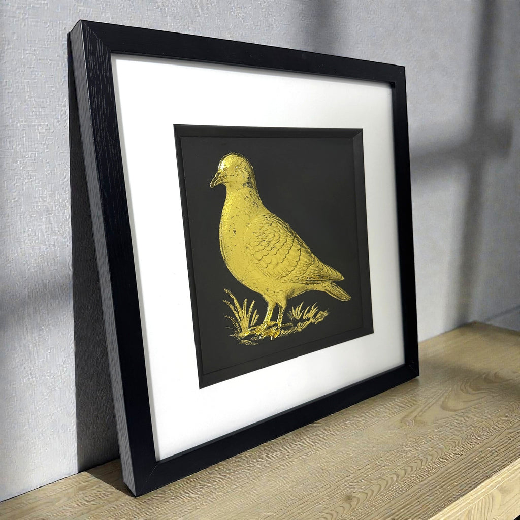 Angled view of gold leaf pigeon wall art showing frame depth, raised relief texture, and metallic highlights