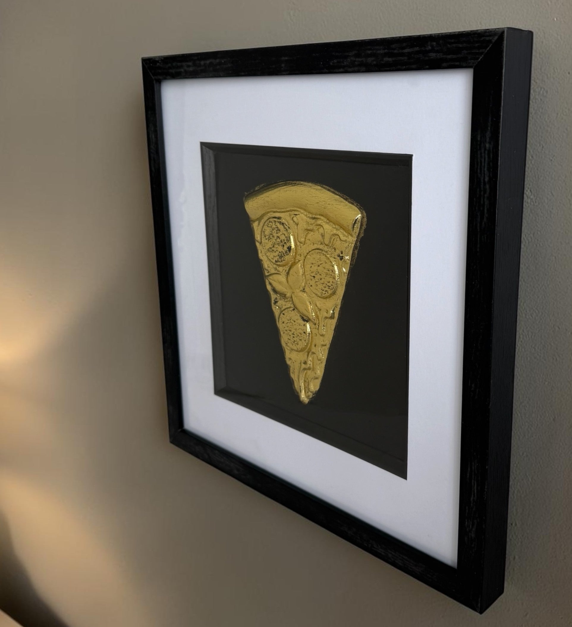 Side view of Gold pizza slice relief artwork showing black box frame depth and wide white mount.