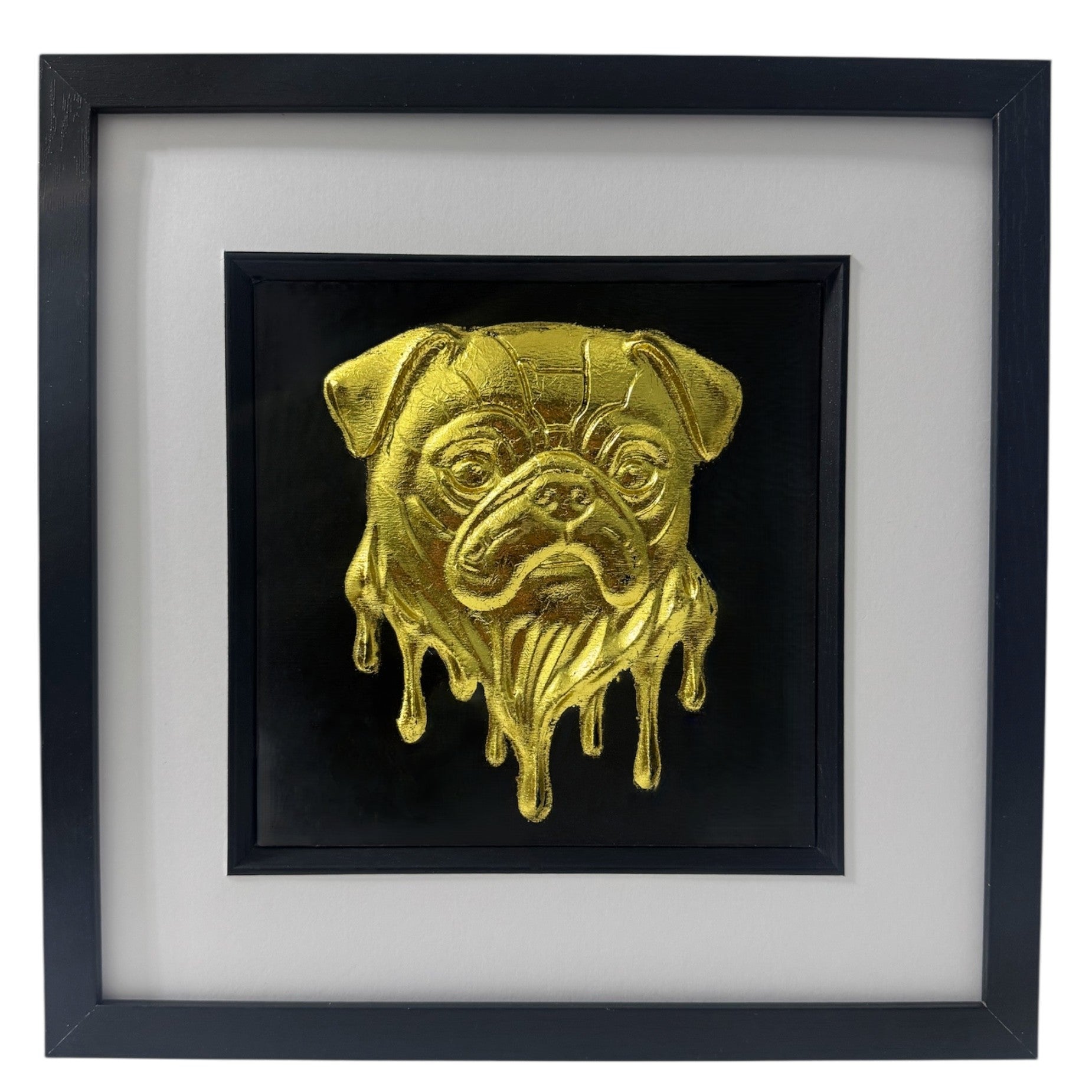 Molten Pug framed wall art in gold leaf shown at an angle on a reflective surface with black wooden frame and white mount