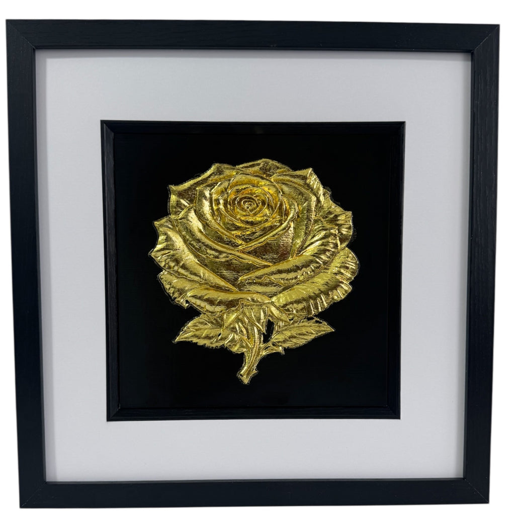 Front-on product photo of framed Gold Leaf rose relief centred on black surround, with wide white mount and black square frame.