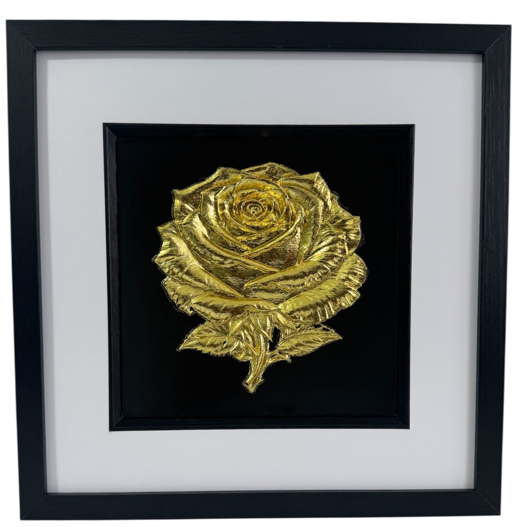 Front-on product photo of framed Gold Leaf rose relief centred on black surround, with wide white mount and black square frame.
