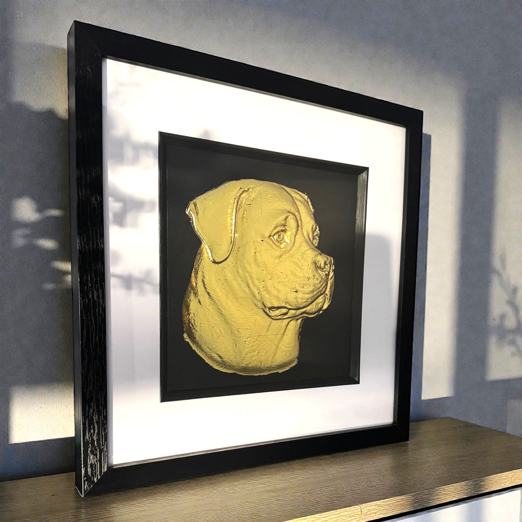 Rottweiler gold leaf wall art photographed at an angle on a shelf with black frame and white mount