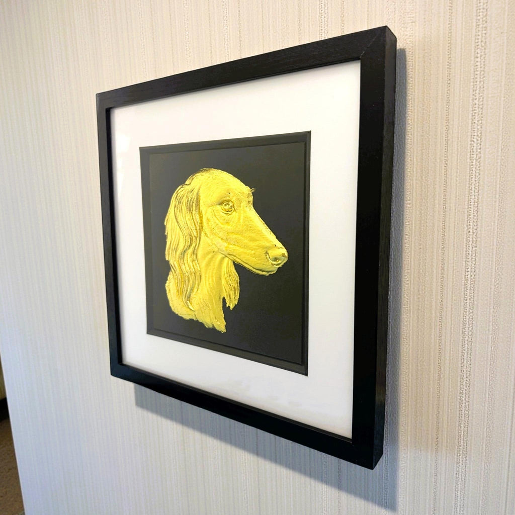 Saluki gold leaf framed wall art mounted on a wall shown at a slight angle with black frame and white mount
