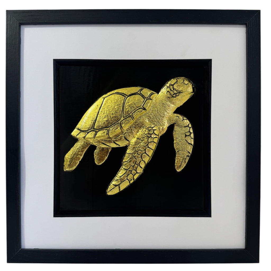 Gold framed sea turtle relief on a black background with a wide white mount and black inner surround