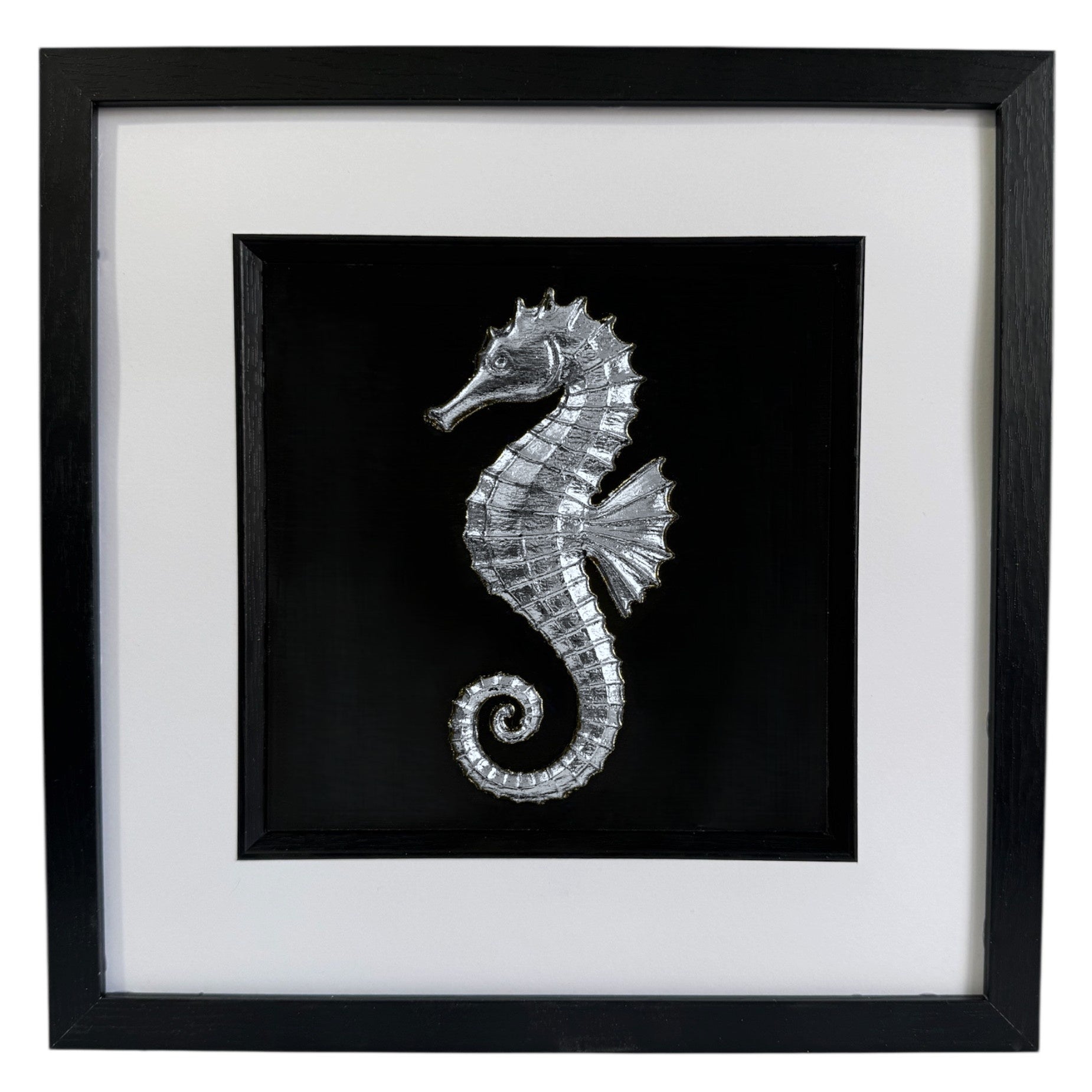 Silver seahorse wall art framed in black with white mount, raised relief seahorse on a black background