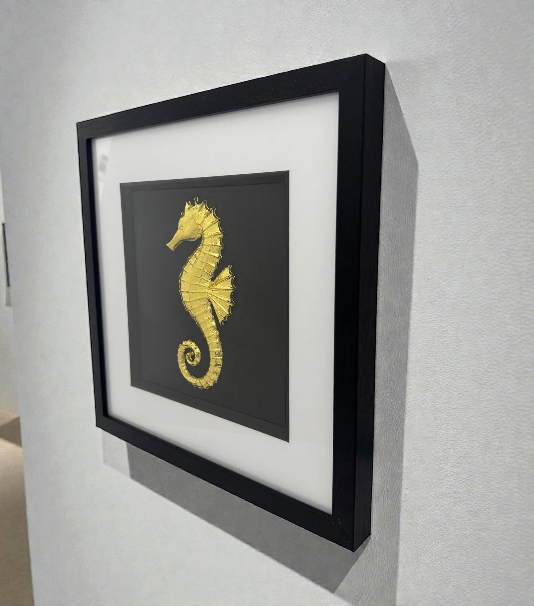 Framed gold seahorse wall art displayed on a wall, black frame with white mount and sculpted marine design