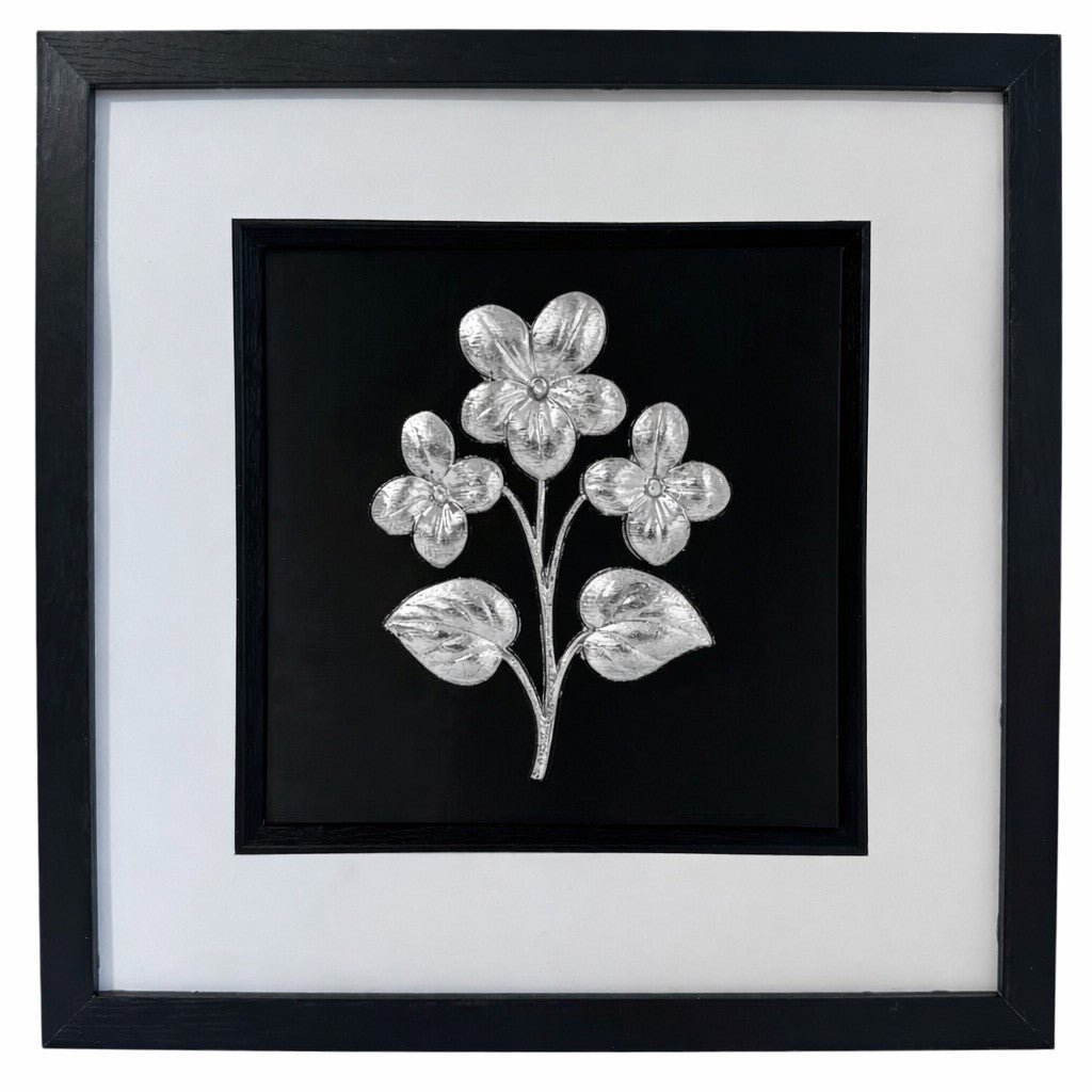 Silver framed floral relief with three flowers and two leaves on a black background with a wide white mount and black inner surround