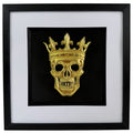 Gold crowned skull artwork with raised relief, black centre, white mount and black square frame.