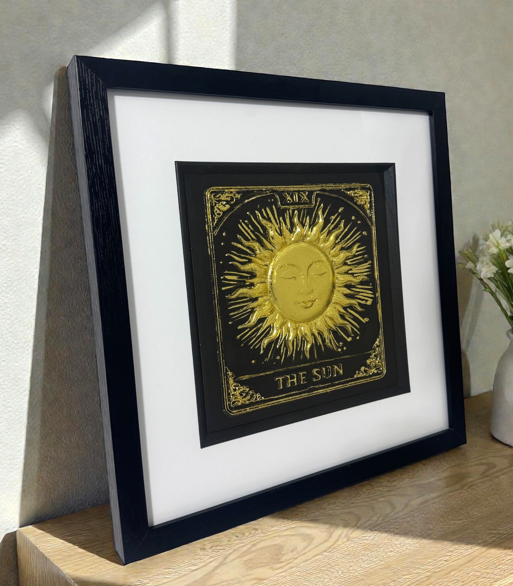 Side angle view of 3D Gold Leaf The Sun Tarot art on a wooden side table, highlighting the metallic shimmer and depth.