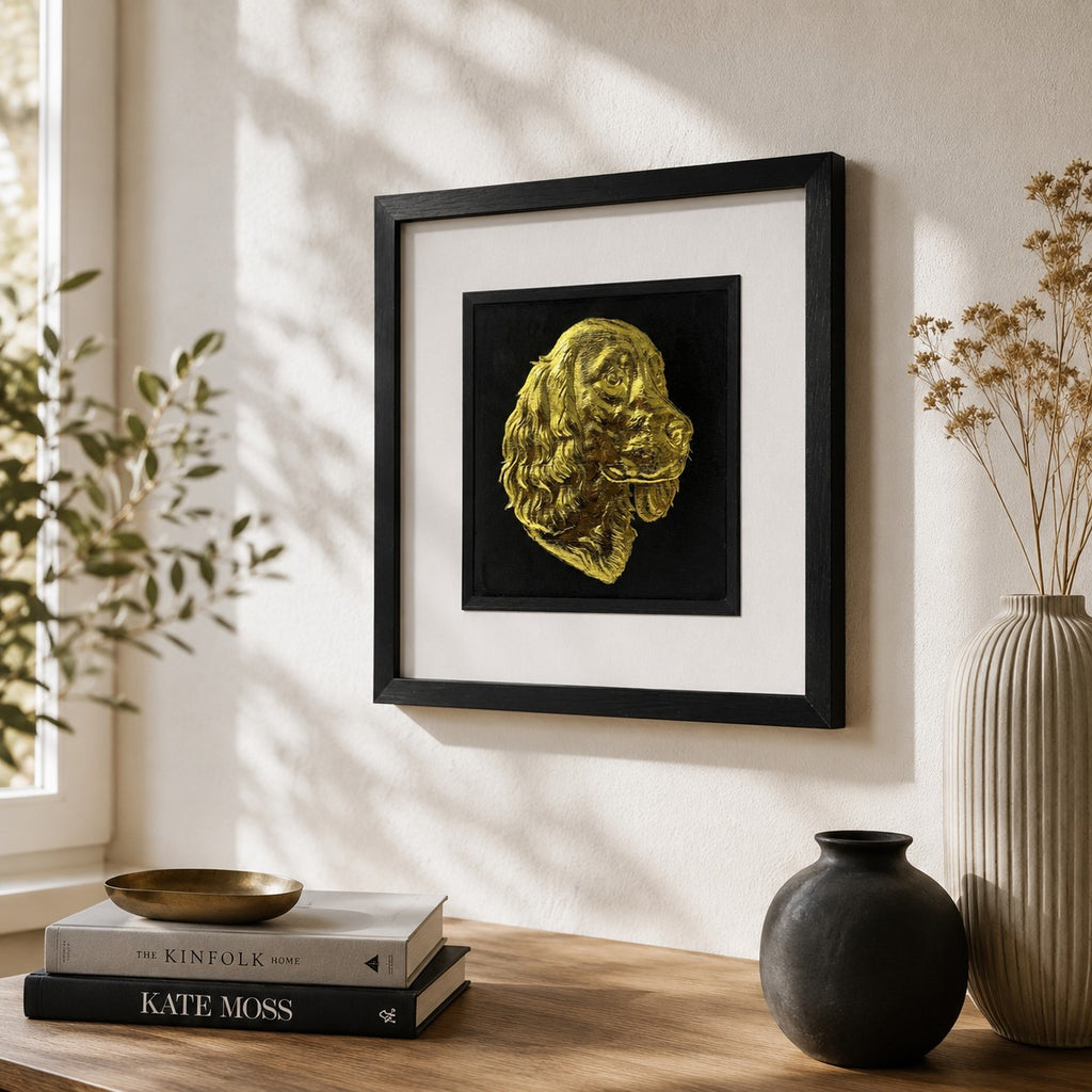 Angled lifestyle view of Springer Spaniel gold leaf 3D wall art in a black frame, displayed on a neutral wall with warm wood, brass and natural decor styling.