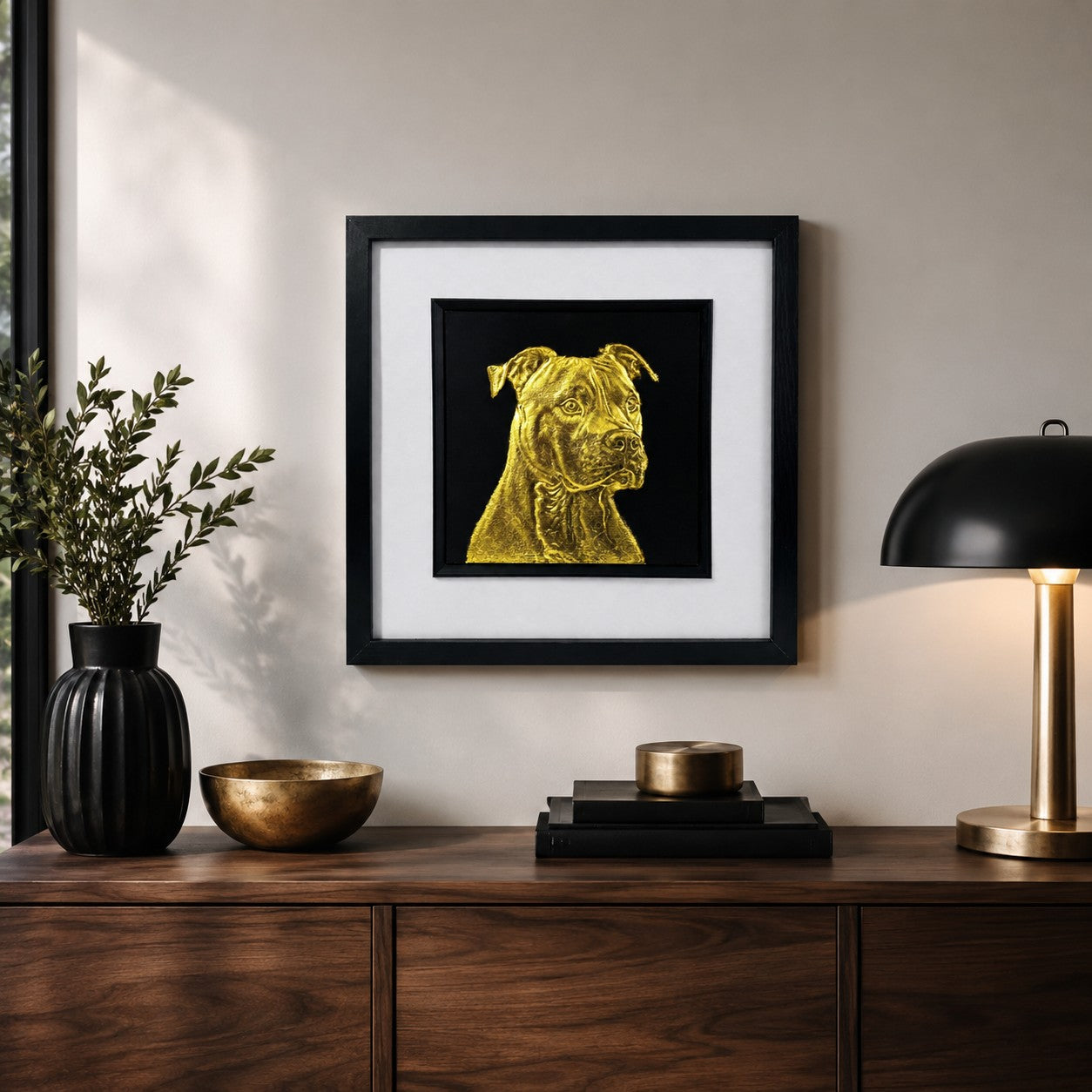 Staffordshire Bull Terrier gold leaf 3D wall art in a black square frame, styled on a neutral wall above a wooden sideboard with black and brass home decor accents.