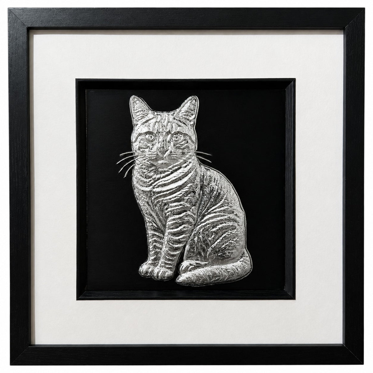 Framed tabby cat wall art, silver relief of a sitting striped tabby with raised whiskers, on a black background in a black wooden frame with white mount