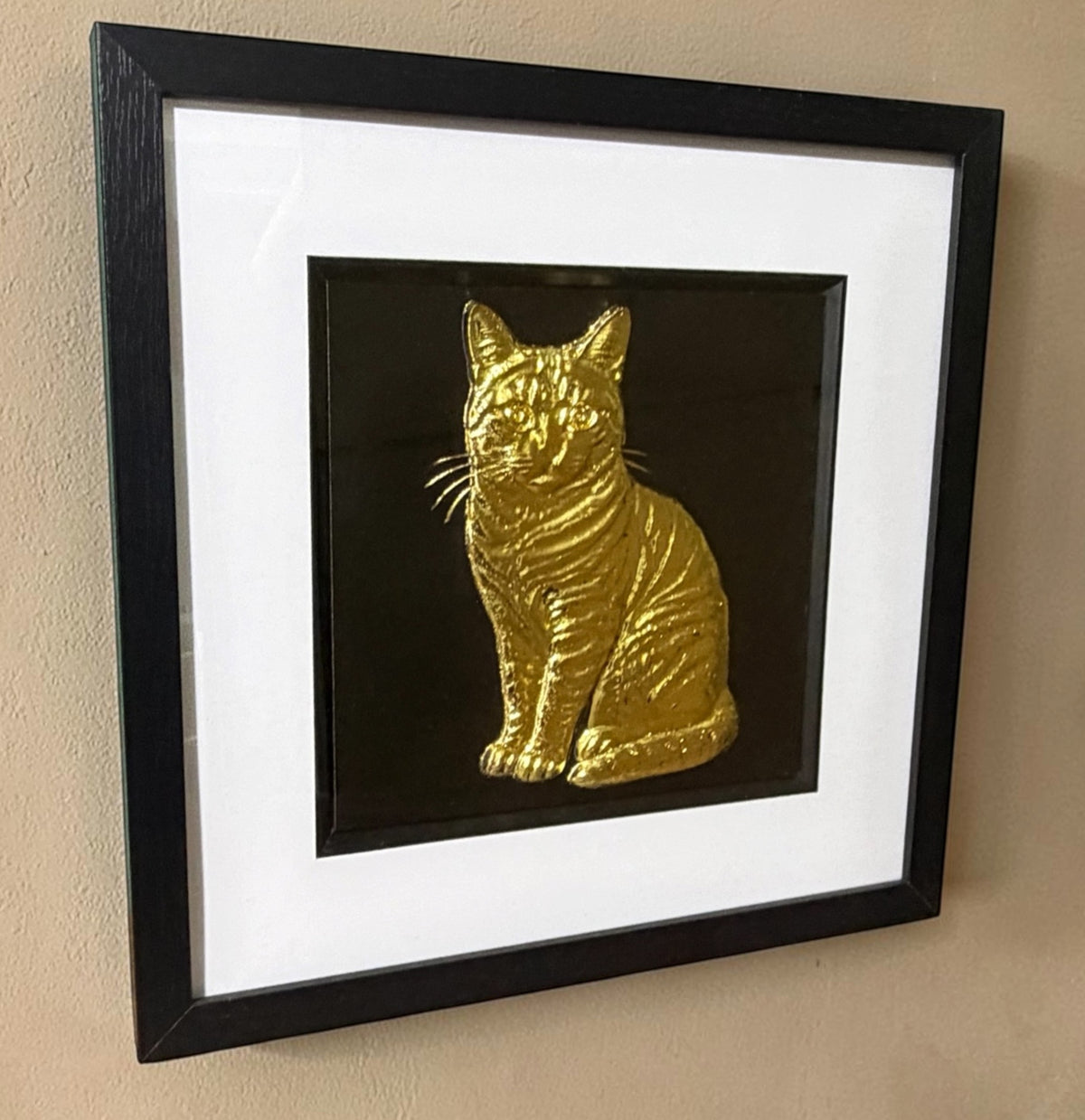 Gold tabby cat 3D wall art hanging on a cream textured wall, viewed from the side to show the depth of the black box frame and the raised stripes