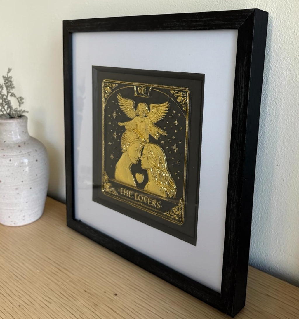 Gold The Lovers tarot framed artwork on a wooden surface with glass front and black box frame