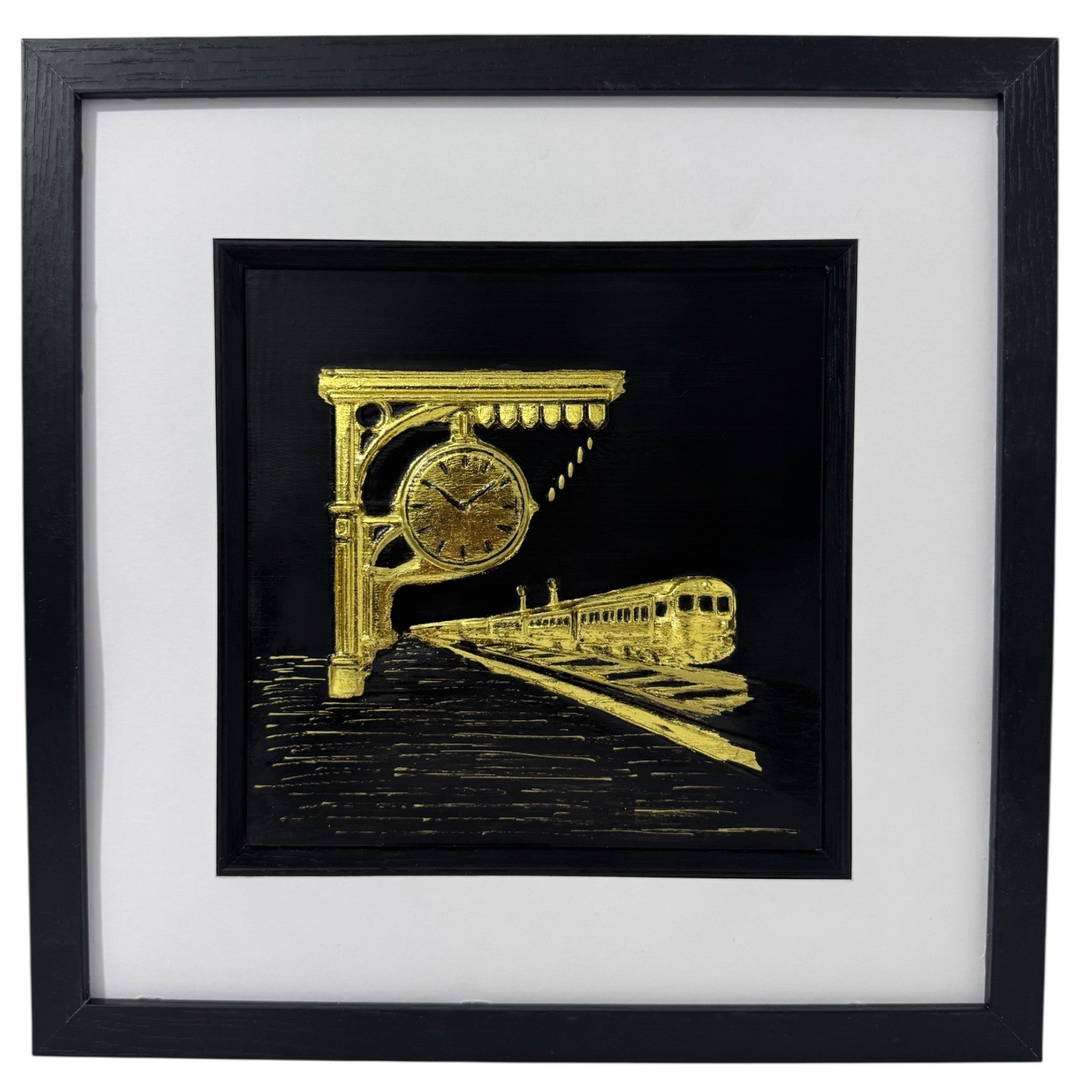 Gold train station relief in a black box frame with wide white mount and black inner surround.