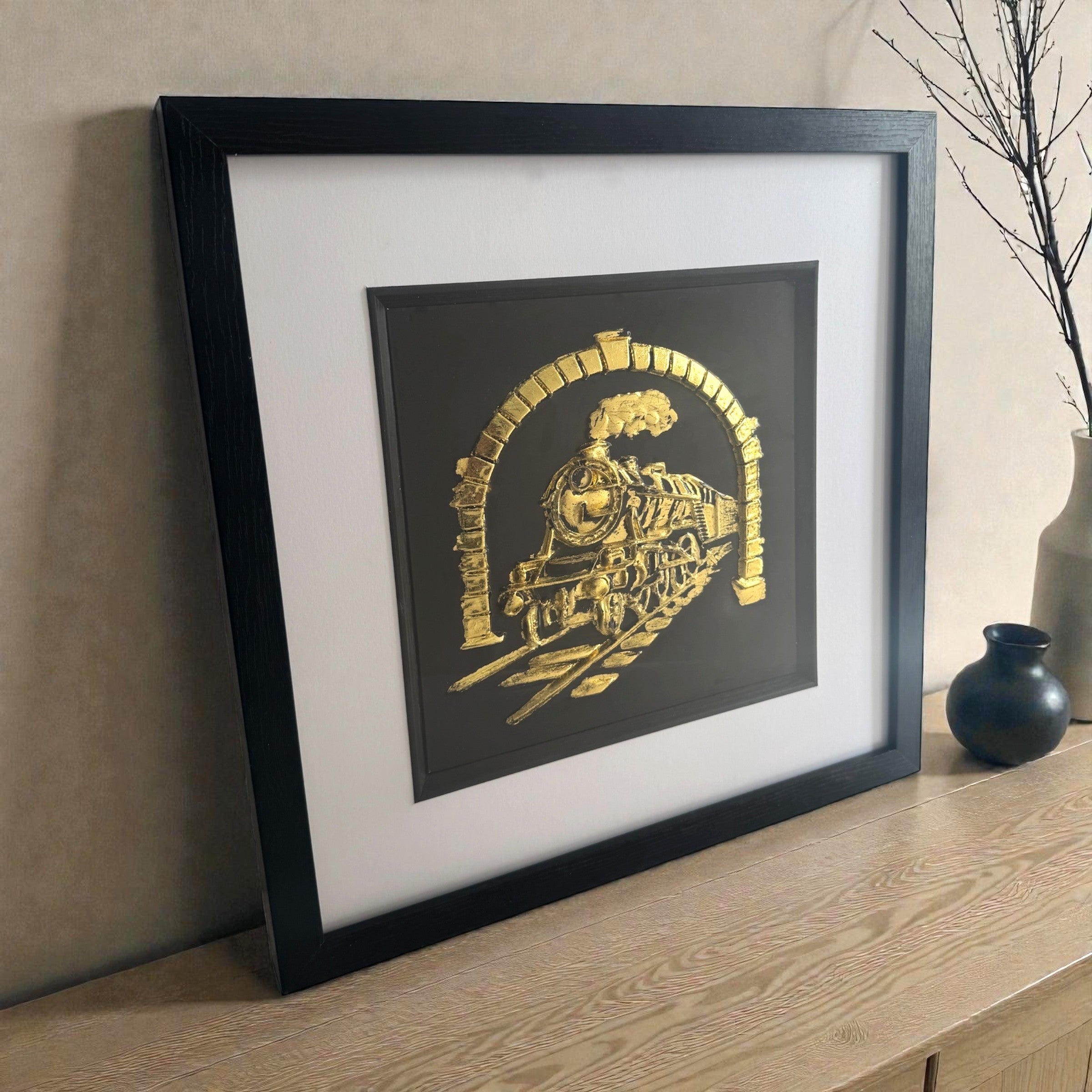 Framed steam locomotive Gold Leaf relief artwork styled on a wooden sideboard, black box frame with white mount and inner black surround