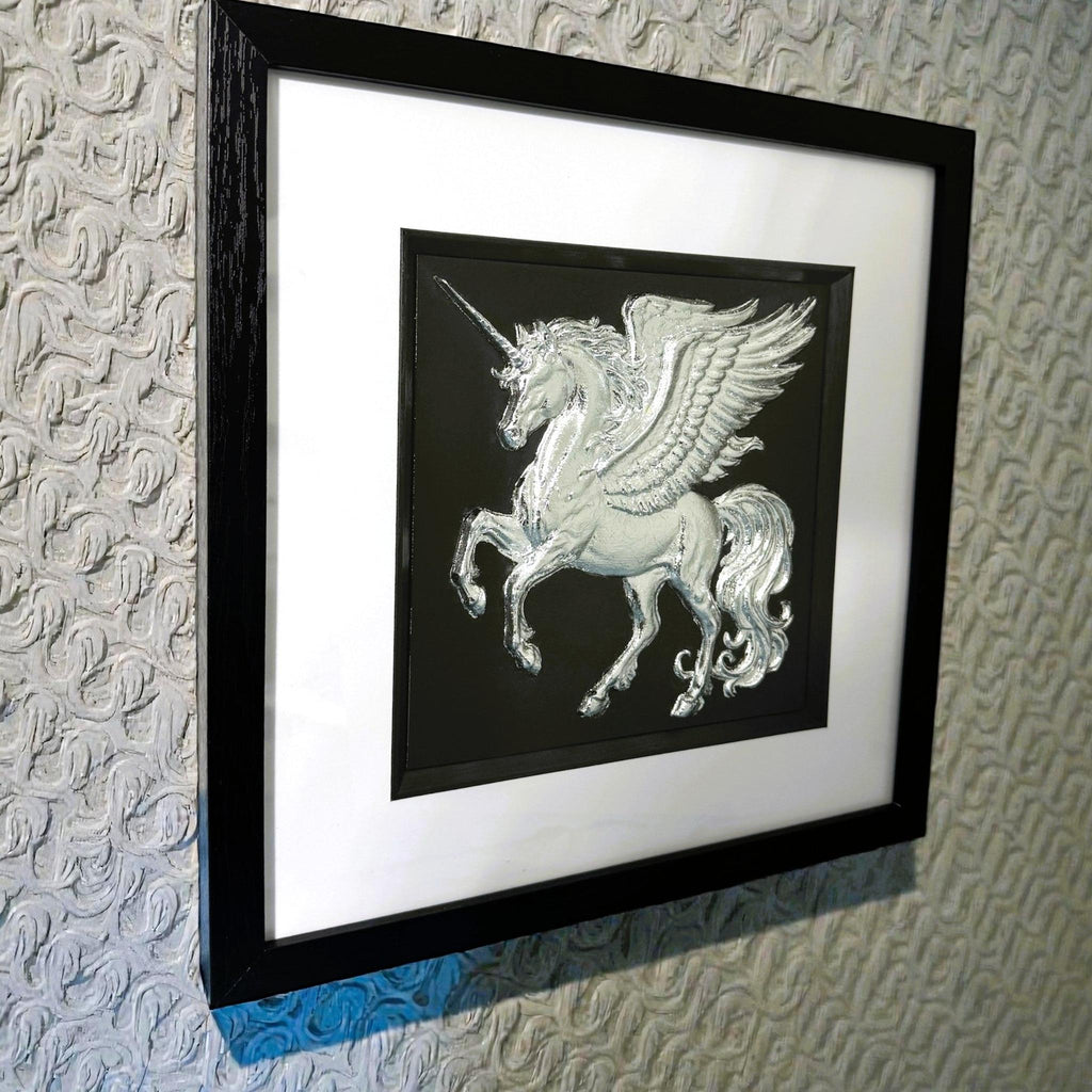 Silver unicorn wall art framed in black displayed on a textured wall