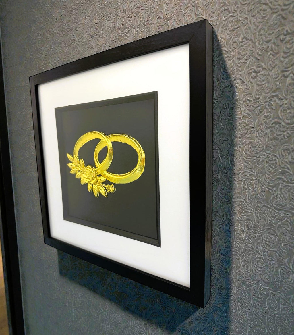 Angled wall-mounted view of wedding rings wall art framed in black with white mount