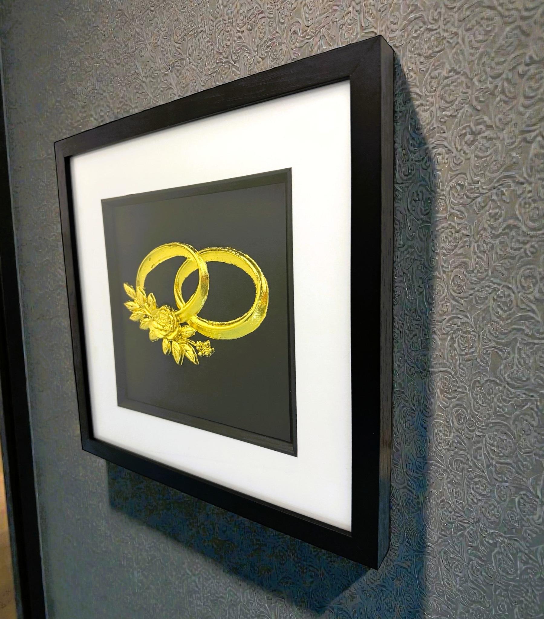 Angled wall-mounted view of wedding rings wall art framed in black with white mount