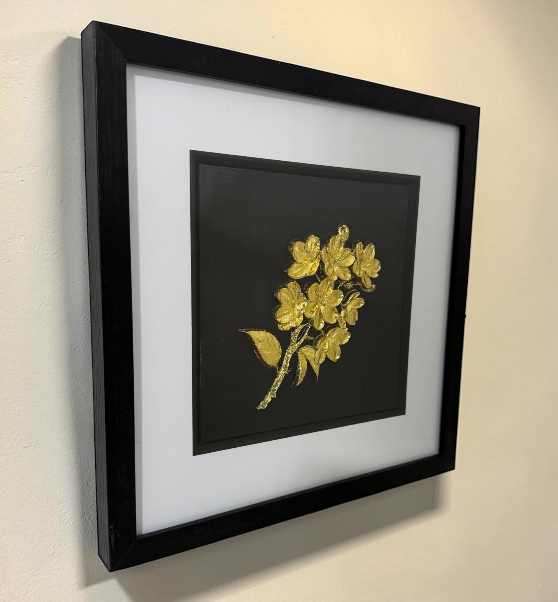 Angled view of gold 3D flower bouquet artwork showing the black box frame, wide white mount, black inner surround and glass front