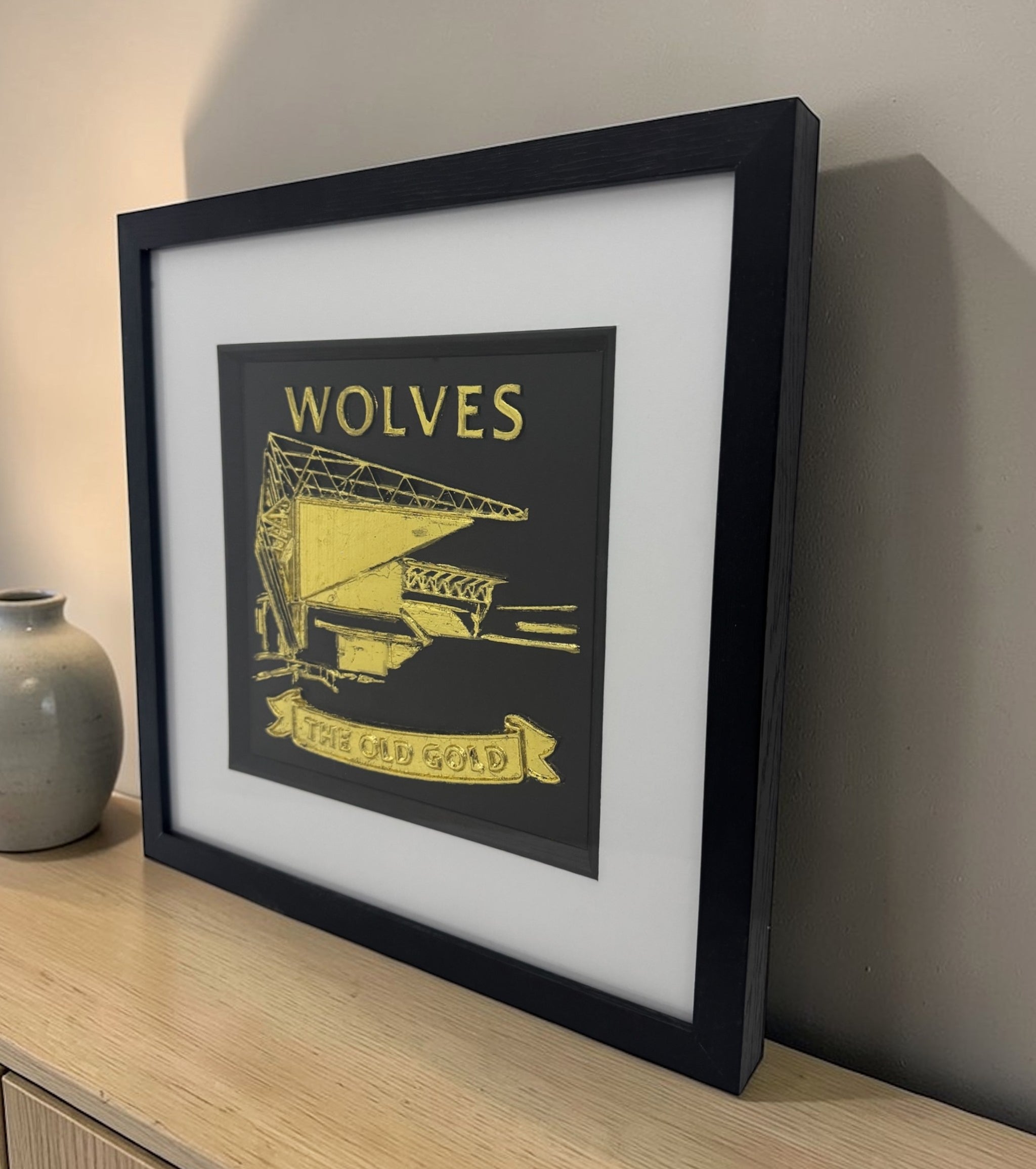 Gold Wolves 3D relief stadium artwork in black square frame with white mount, angled view on shelf